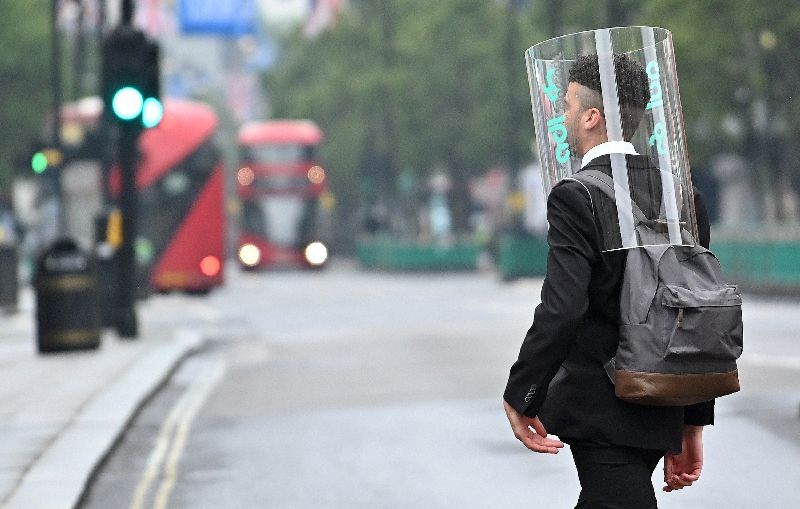 A pedestrian wearing a form of PPE (personal protective equipment) of a perspex full-face covering, as a precautionary measure against COVID-19, walks across Oxford Street in central London , (Photo by Justin Tallis/AFP Photo)